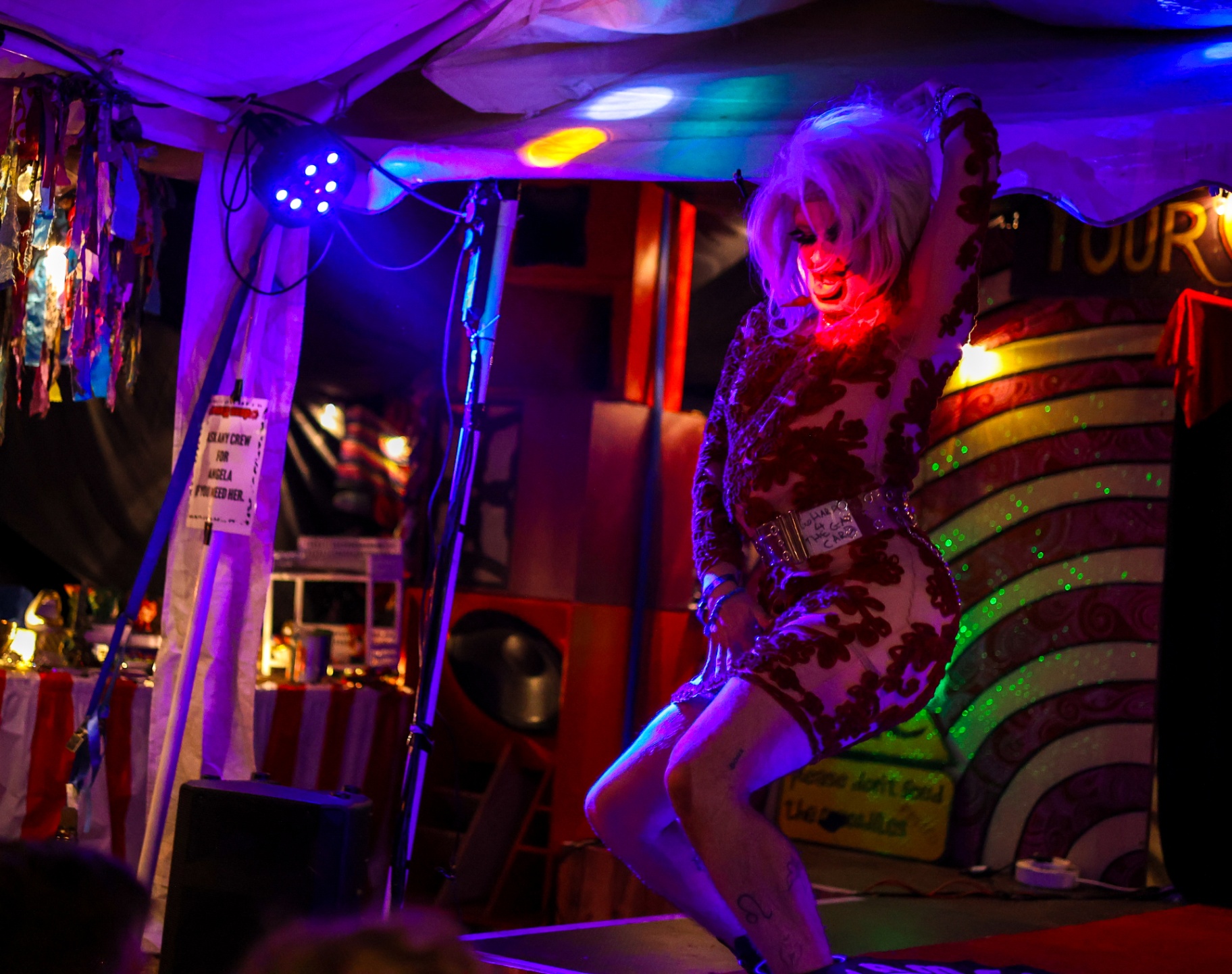 Performer in a blonde wig dancing on a festival stage platform