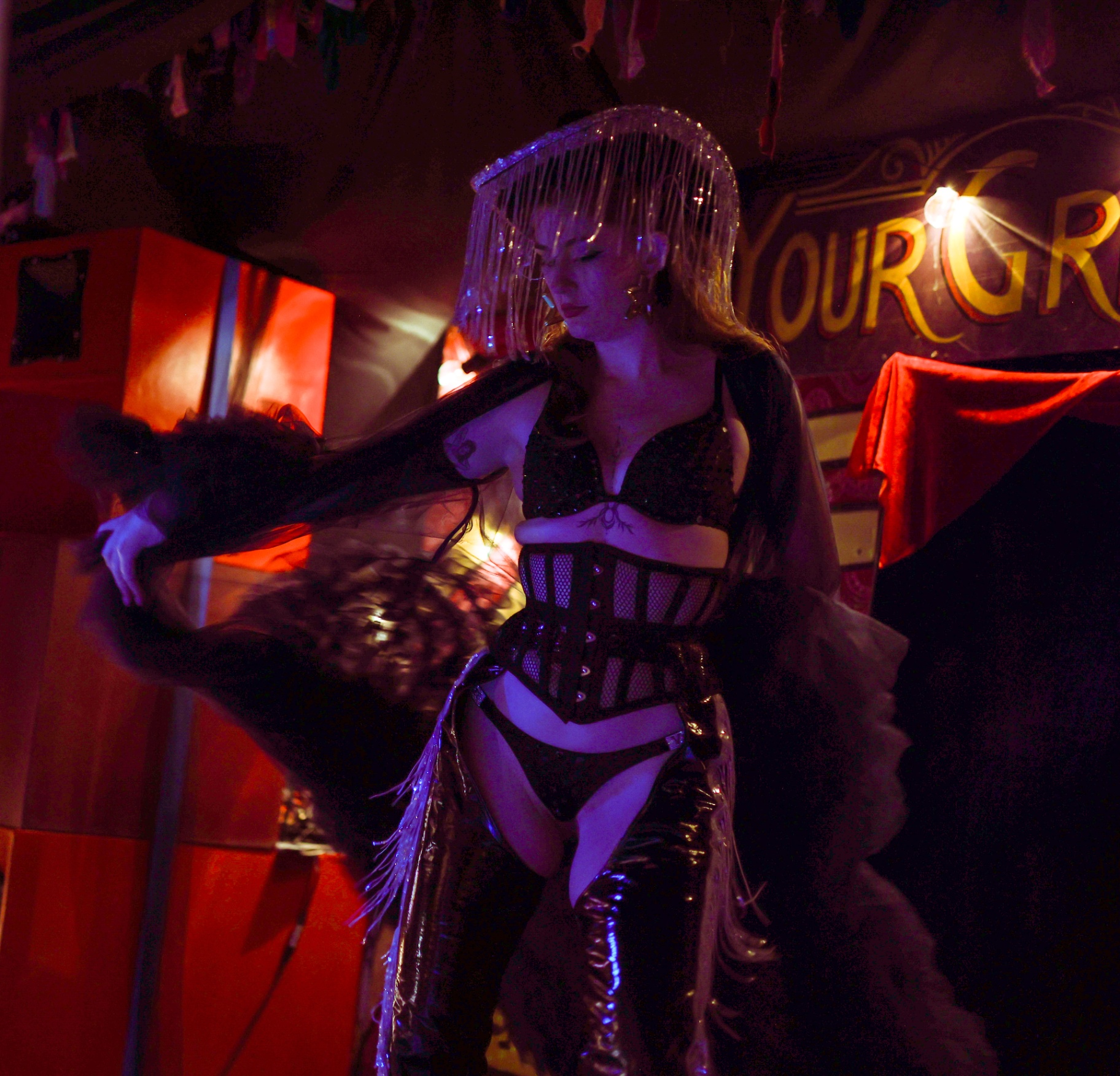 Cabaret performer in a fringed headpiece and corset on a festival stage