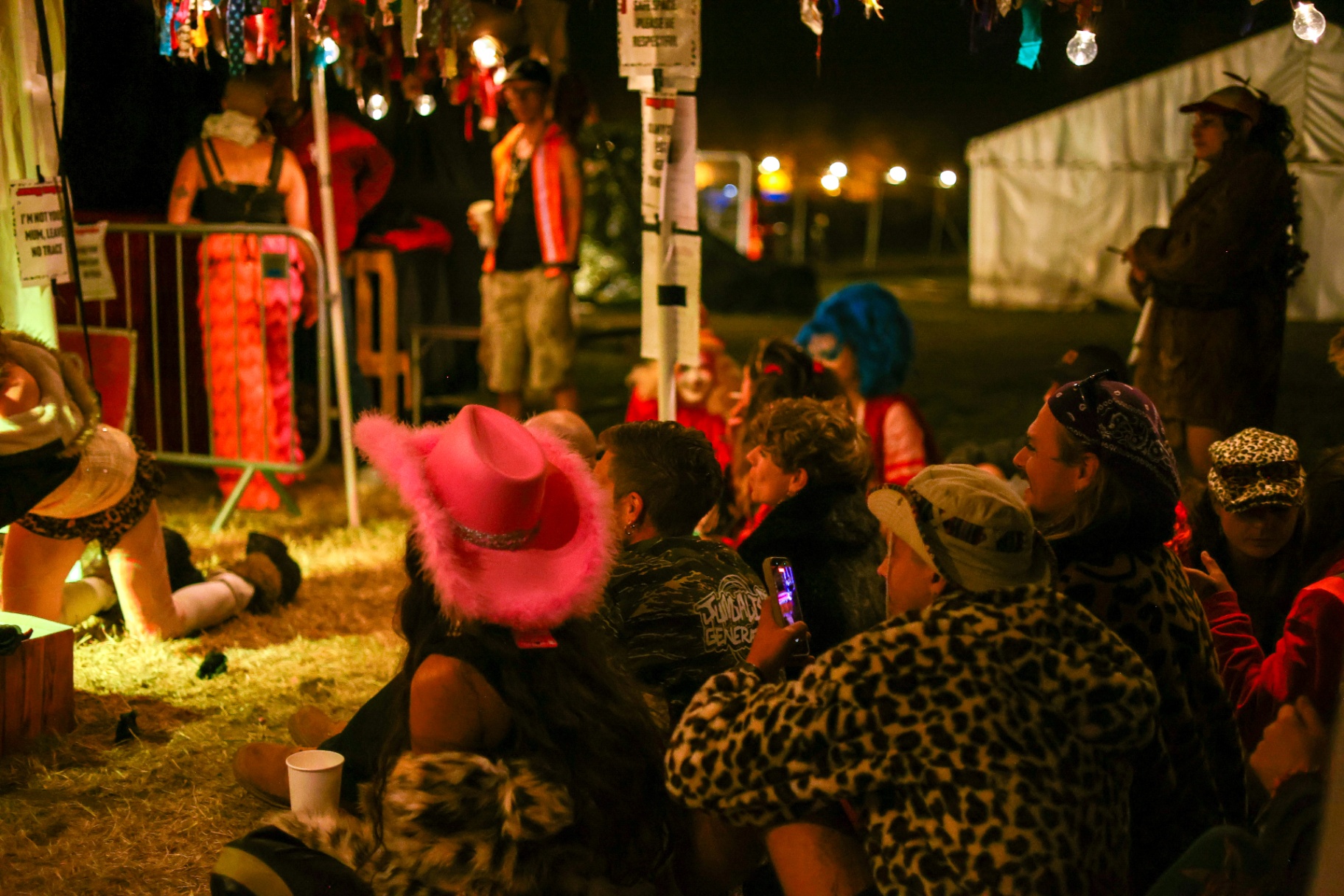 Festival-goers watching an evening performance under string lights